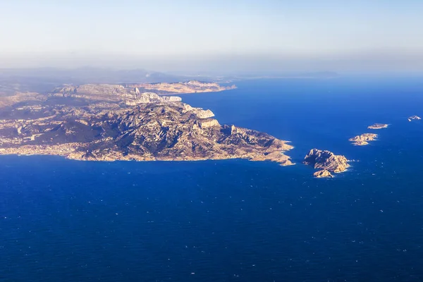 Deniz kıyısı bir sis içinde engebeli arazide. Büyük yükseklikte uçan uçak penceresinden bir görünüm