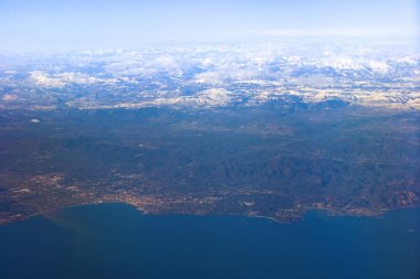 Deniz kıyısı bir sis içinde engebeli arazide. Büyük yükseklikte uçan uçak penceresinden bir görünüm