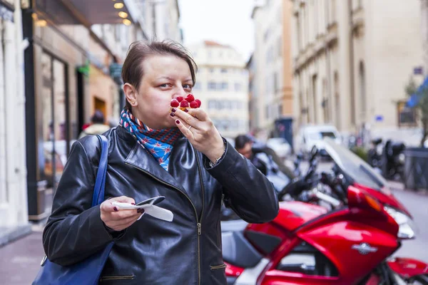 MARSEILLE, FRANCE, on March 2, 2018. The young attractive woman eats tasty cake on the picturesque street