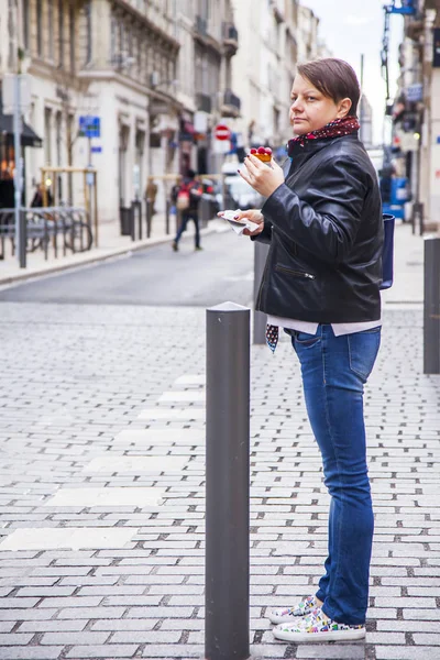 MARSEILLE, FRANCE, on March 2, 2018. The young attractive woman eats tasty cake on the picturesque street