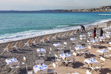 Güzel, Fransa, 7 Mart 2018. Bir su kenarında kumsalda beyaz küçük tablolar pitoresk Kafe'nin yerleşti