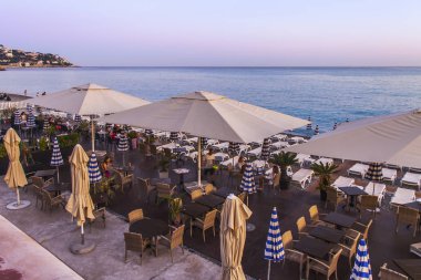 Güzel, Fransa, 14 Ekim 2019. Akdeniz 'de gün batımının resmi gibi. Gün batımı güneşiyle aydınlatılan bir sahildeki kafe masaları.