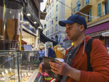 Güzel, Fransa, 10 Ekim 2019. Genç bir adam eski kasabadaki tipik bir sokak kafesinden dondurma alır.