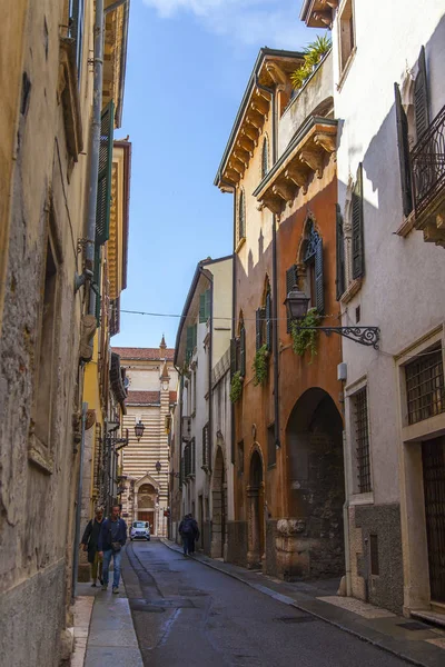 Verona, İtalya, 24 Nisan 2019 tarihinde. İnsanlar eski şehirde dar pitoresk sokak boyunca gitmek