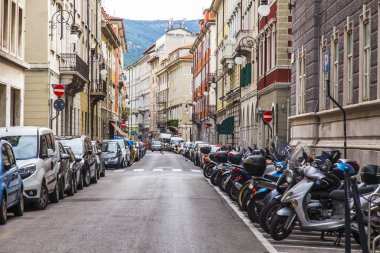 Trieste, İtalya, 5 Ağustos 2019. Tarihi şehirde güzel bir resim caddesi. Arabalar ve motosikletler kaldırımın kenarına park edilmiş.