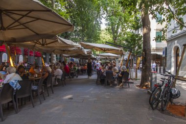 Trieste, İtalya, 7 Ağustos 2019. Tarihi şehirde pitoresk bir caddenin kaldırımında çekici kafe masaları.
