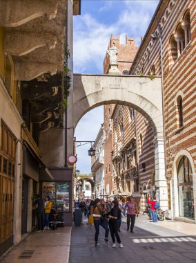 Verona, İtalya, 24 Nisan 2019 tarihinde. İnsanlar eski şehirde dar pitoresk sokak boyunca gitmek