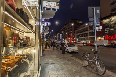 Milan, İtalya, 12 Şubat 2020. Şehir merkezindeki alışveriş caddesinde akşam aydınlığında. Çok sayıda mağazanın vitrinleri zarif vitrinlerle alıcıları cezbediyor