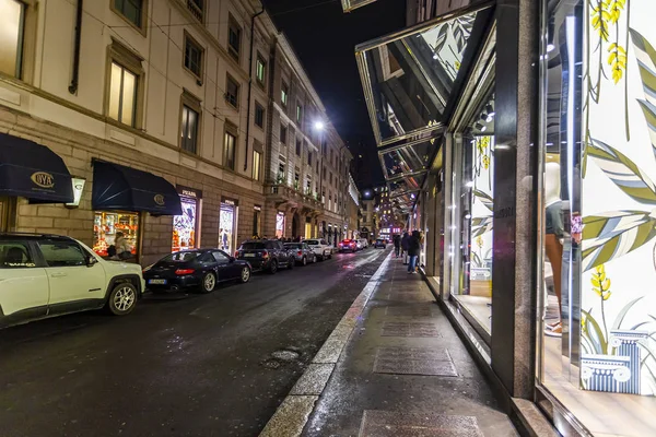 Milan, İtalya, 12 Şubat 2020. Şehir merkezindeki alışveriş caddesinde akşam aydınlığında. Çok sayıda mağaza akıllı vitrinli müşterileri çekiyor.