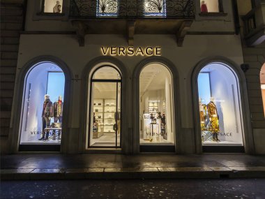 Milan, İtalya, 12 Şubat 2020. Şehir merkezindeki alışveriş caddesinde akşam aydınlığında. Çok sayıda mağazanın vitrinleri zarif vitrinlerle alıcıları cezbediyor