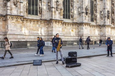 Milan, İtalya, 12 Şubat 2020. Şehrin ilgi odağı katedral (İtalyanca: Duomo di Milano veya Cattedrale di Santa Maria Nascente) Duomo meydanının önündeki sokak müzisyenidir.