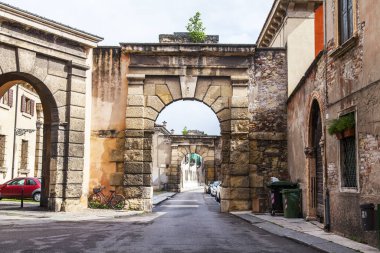 Verona, İtalya, 24 Nisan 2019. Şehir merkezinin tarihi bölümünde taş kemerli dar resimli cadde. Tipik şehir silüeti
