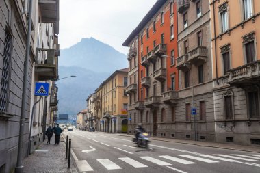Lecco, İtalya, 16 Şubat 2020. Tarihi bir binada tipik şehir manzarası. İnsanlar güzel bir caddede yürüyorlar.