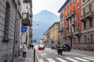 Lecco, İtalya, 16 Şubat 2020. Tarihi bir binada tipik şehir manzarası. İnsanlar güzel bir caddede yürüyorlar.