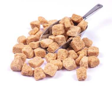 Beyaz bir masada metal kaşıkta kahverengi kamış şekeri