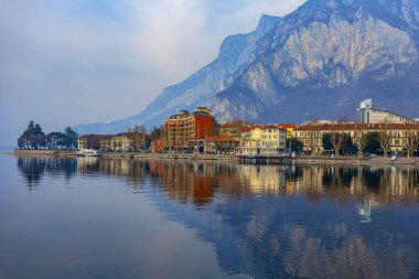 Lecco, İtalya, 16 Şubat 2020. Como Gölü 'nün bulutlu havadaki manzaralı seti ve arkasındaki dağlar. Suda güzel bir yansıma