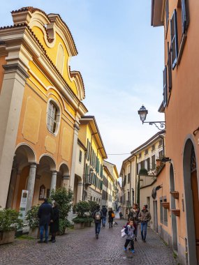 Lecco, İtalya, 16 Şubat 2020. Tarihi bir binada tipik şehir manzarası. İnsanlar güzel bir cadde boyunca yürür