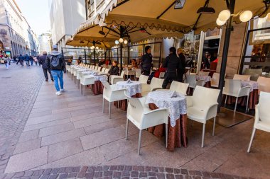 Milan, İtalya, 12 Şubat 2020. Tarihi şehirde çekici bir kafe. İnsanlar kaldırımdaki masalarda yer ve dinlenir..