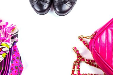 Pembe kadın çantasının parçaları, siyah ayakkabılar ve desenli eşarpla yatıyordu.