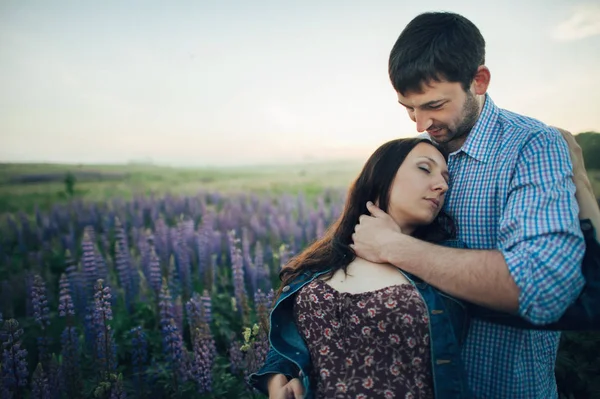 Pareja joven en flores púrpuras — Foto de Stock