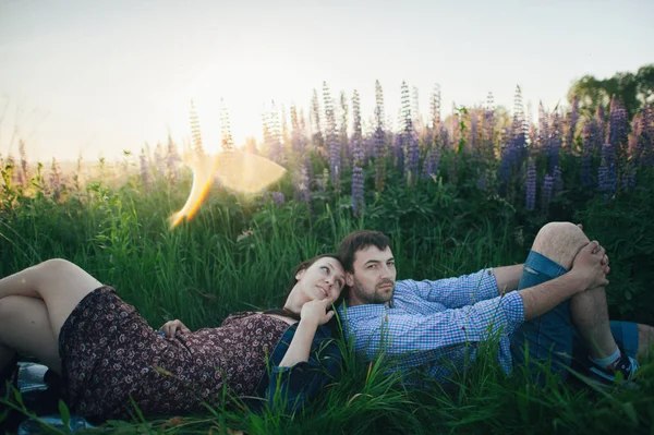 Pár ležící v trávě a květiny — Stock fotografie