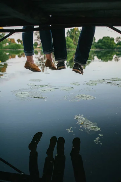 Legs of couple overhanging from bridge — Stock Photo, Image