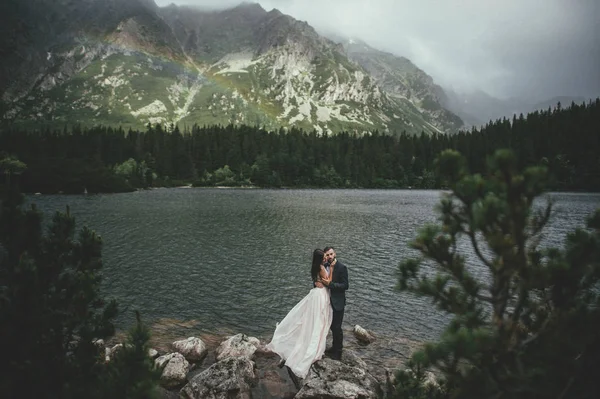 Felices recién casados en la costa del lago de montaña — Foto de Stock