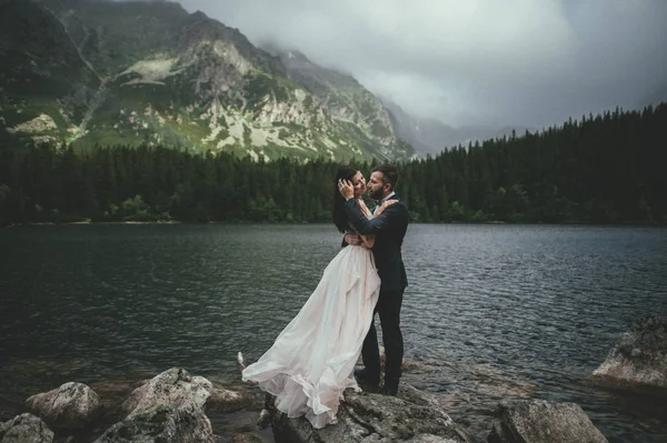 Heureux jeunes mariés sur la côte du lac de montagne — Photo