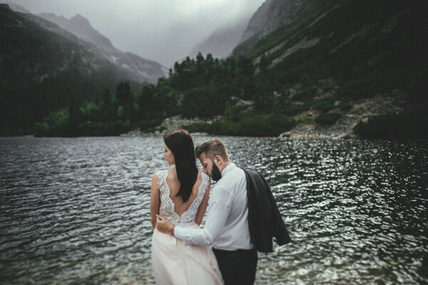 happy newlyweds on coast of mountain lake 