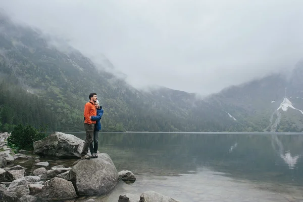 Пара путешественников, стоящих на скале у озера — стоковое фото