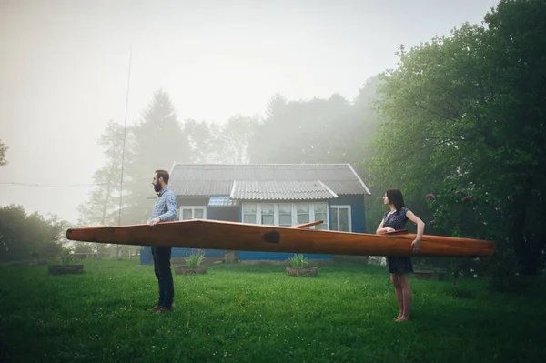 Romantic couple in love holding wooden canoe — Stock Photo, Image