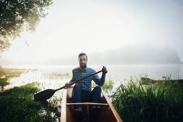 Homem com remo sentado na canoa — Fotografia de Stock