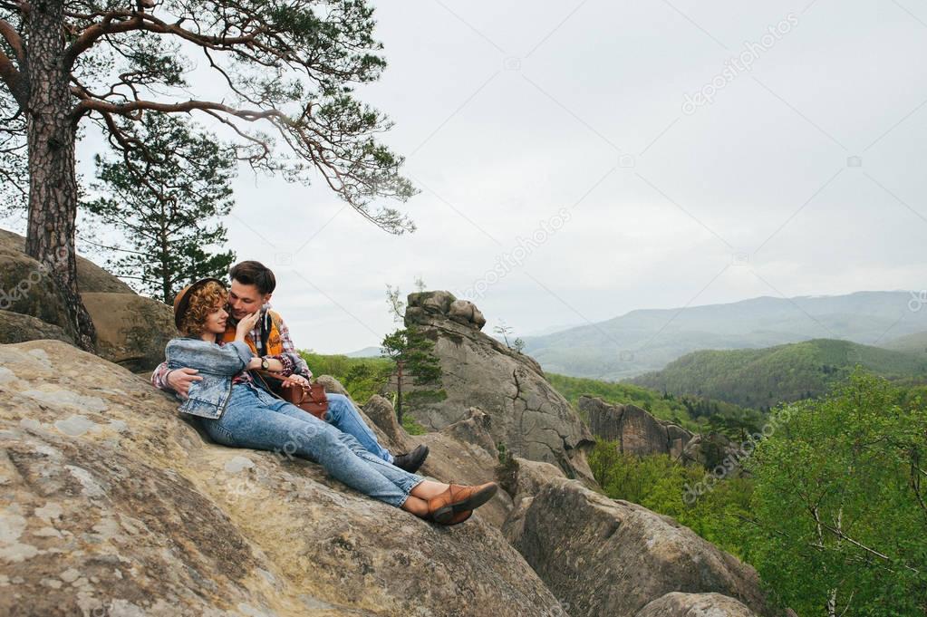 traveler couple sitting on edge of mountain