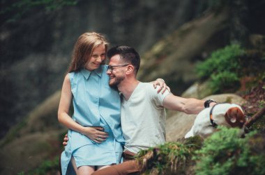 Çift kayanın üzerinde oturan ve köpek sevişme