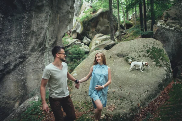Pareja caminando con el perro en la colina del bosque — Foto de Stock