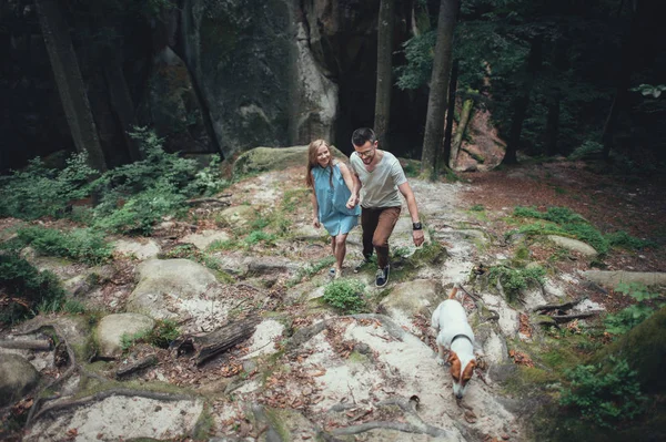 Casal andando com cão na colina da floresta — Fotografia de Stock