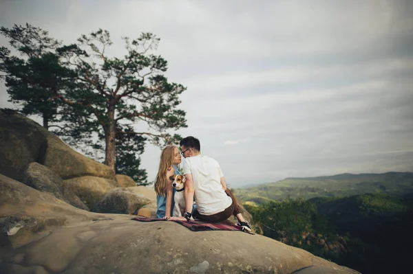 Paar sitzt mit Hund auf Picknickdecke — Stockfoto