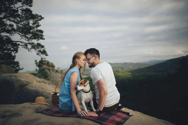 Pareja sentada en una manta de picnic con perro — Foto de Stock