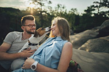 Piknik battaniyesi ile köpek oturan Çift