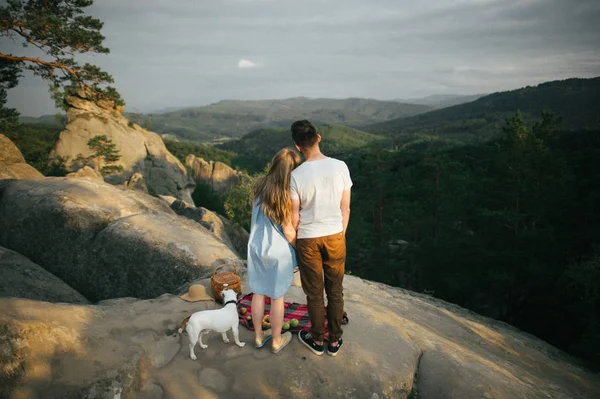 Casal com cão olhando para a vista montanhas — Fotografia de Stock