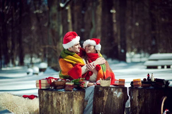 Couple in red hats cuddling on glade — Stock Photo, Image