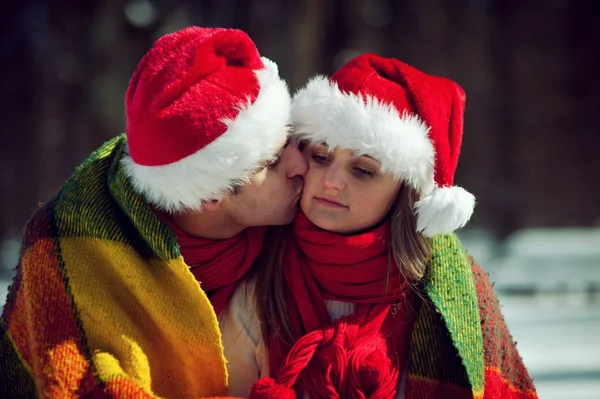 Couple in red hats wrapped in plaid — Stock Photo, Image