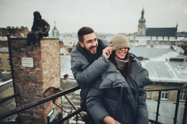 Feliz Jovem Casal Abraçando Telhado Cidade Homem Colocando Chapéu Mulher — Fotografia de Stock