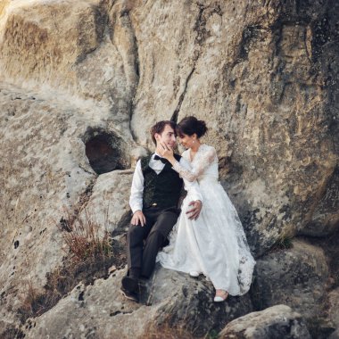 kayanın üzerinde oturan ve sarılma genç çekici beyaz nişanlı Çift