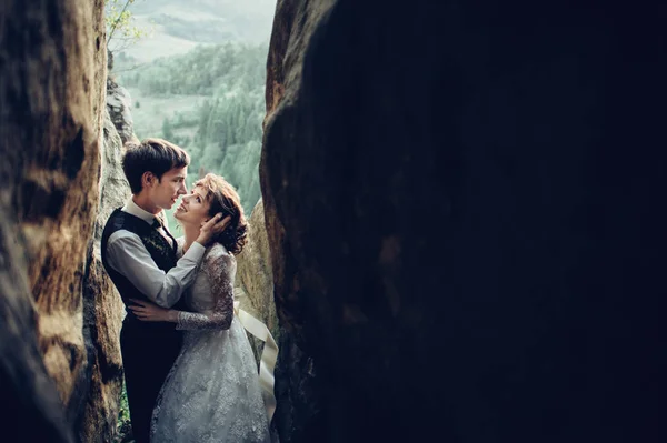 young attractive caucasian engaged couple hugging and looking at each other in mountains