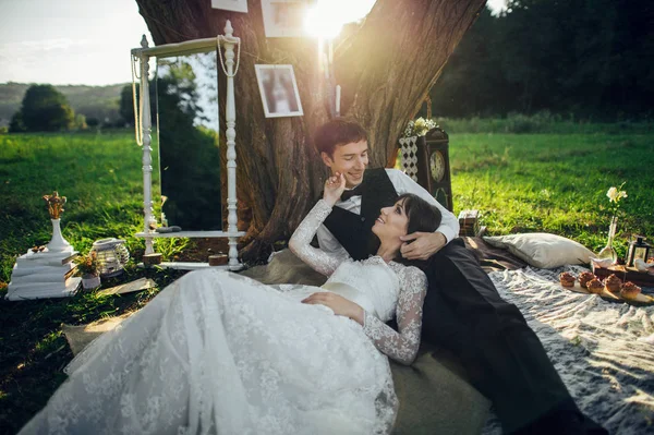 young caucasian engaged couple lying on romantic picnic under tree