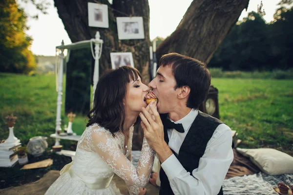 young attractive caucasian engaged couple eating cupcake together on romantic picnic at park