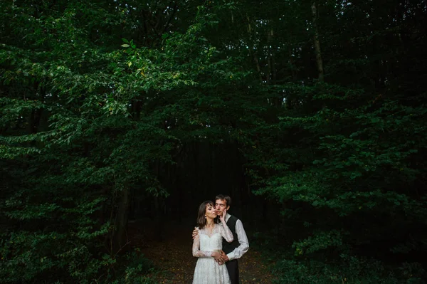 young attractive caucasian engaged couple hugging in deep forest