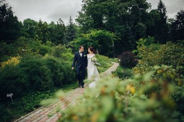 Genç beyaz düğün çift Park'ta yürüyordunuz çiçek buketi ile