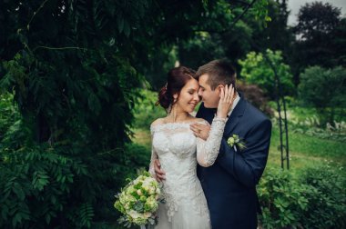 Genç beyaz düğün çifti ile parkta sarılma çiçek buketi